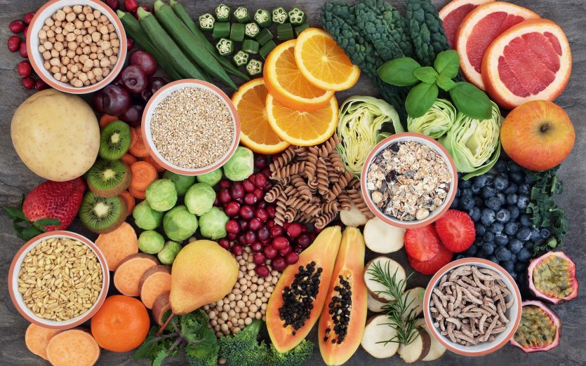 Concepto de alimentos saludables para una dieta rica en fibra con frutas, verduras, cereales, pasta integral, granos, legumbres y hierbas. Alimentos ricos en antocianinas, antioxidantes, hidratos de carbono inteligentes y vitaminas sobre fondo de mármol vista superior.