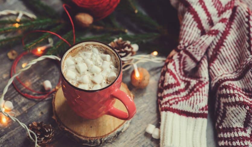 christmas table top view with hot cocoa, warm knitted sweater and garland. Cozy winter morning at home