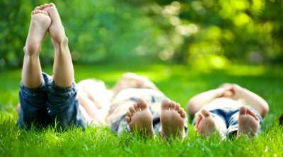 Group of happy children lying on green grass outdoors in spring park