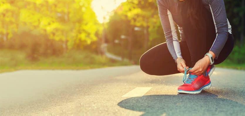 Female runner tying her shoes preparing for a run a jog outside