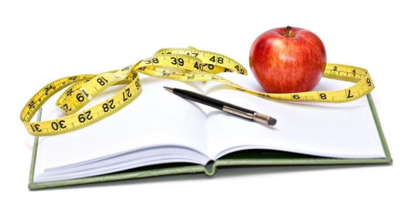 Journal, tape measure and apple - diet concept