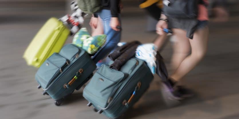 Three young persons with suitcases in blurred motion