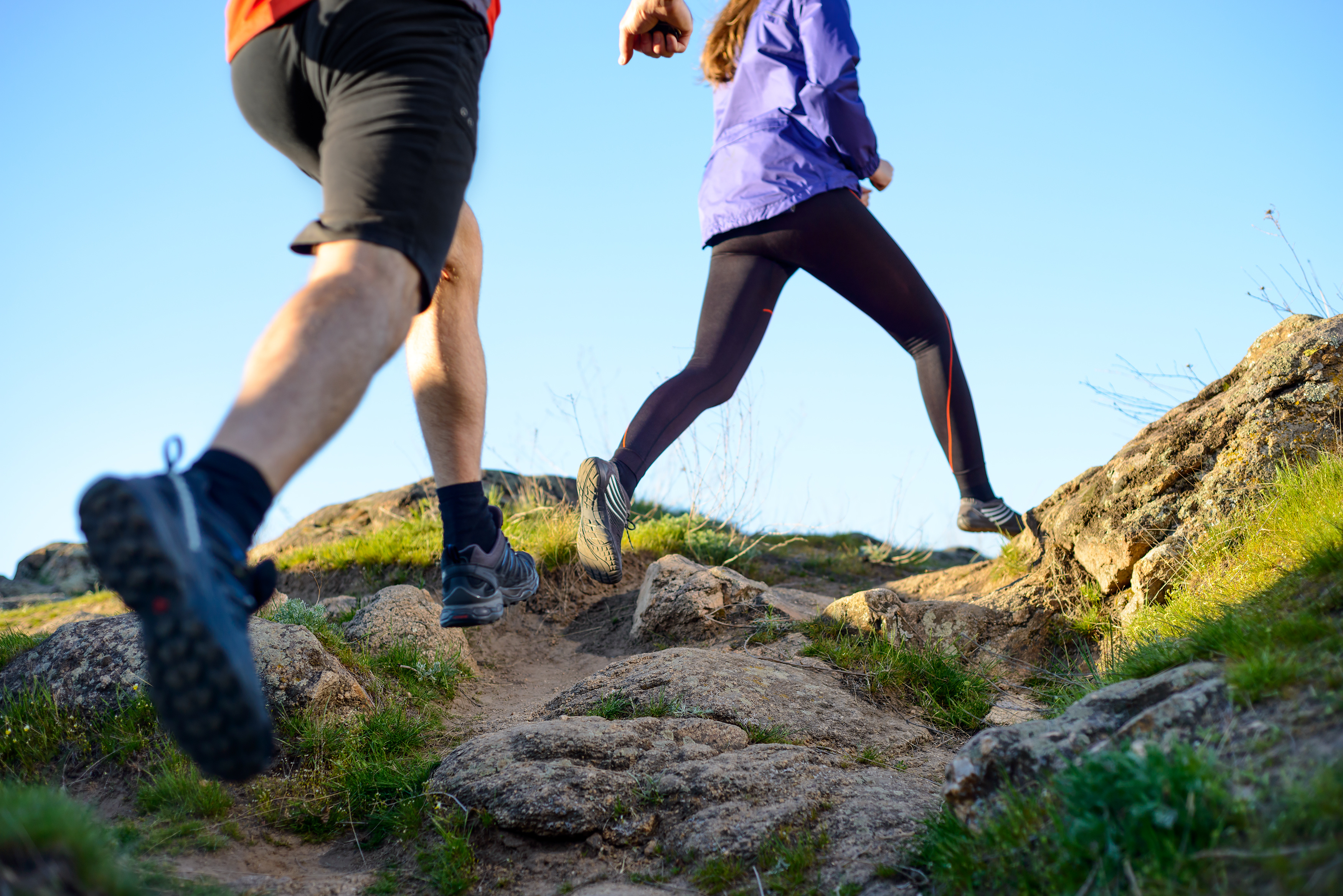 Young Couple Running on the Rocky Trail in Mountains in the Morning