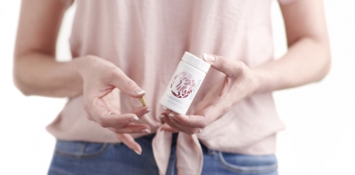 woman holding bottle of EstroPro and a tablet in front of her torso