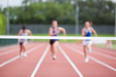 Female athletes running towards finish line on track field